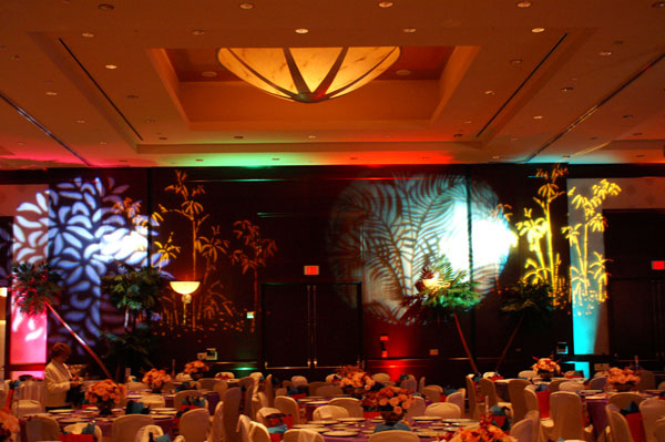 A banquet room with many tables and decorative floral lighing.