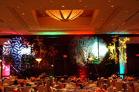 A banquet room with many tables and decorative floral lighing.